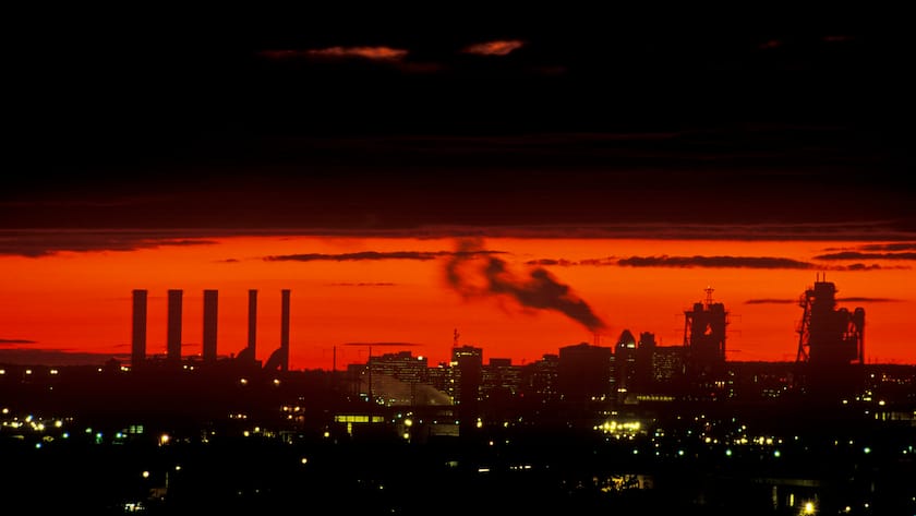 Aktienmärkte im Krisenmodus: Folgt bald auch noch ein Inflationsschock? Industrieller Sonnenuntergang mit Schornsteinen über Newark, USA (2023).