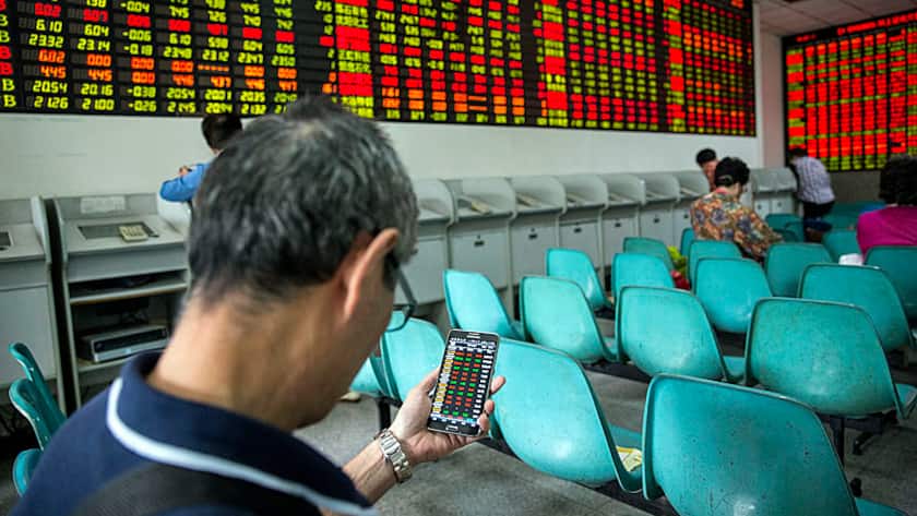 Ein chinesischer Anleger vergleicht die Börsenkurse.