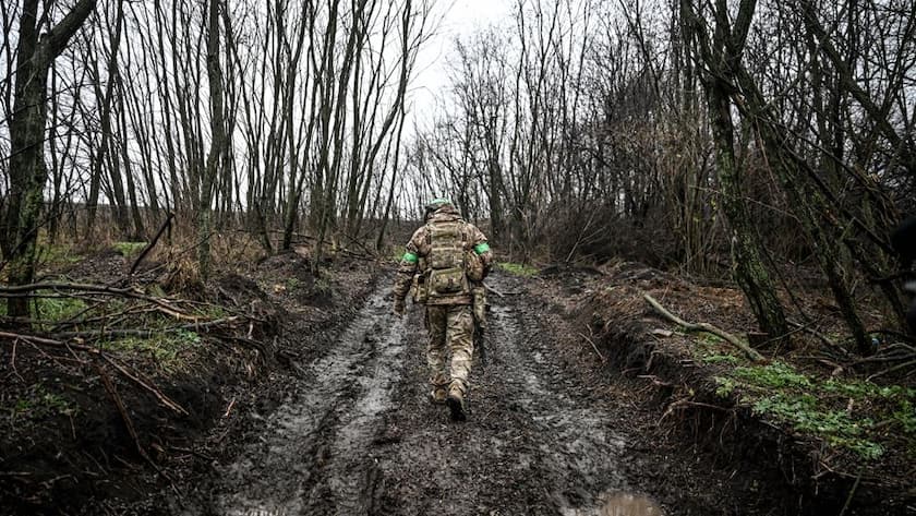 Friedensgespräche zur Ukraine wegen Iran-Krieg unterbrochen Ein Soldat marschiert während eines Kampfeinsatzes in Richtung Pokrowsk auf einer schlammigen Strasse zwischen Bäumen (Ukraine, November 2025).